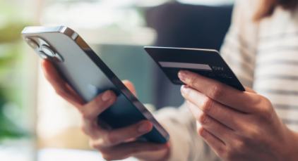 Person holding their phone in one hand and credit card in the other
