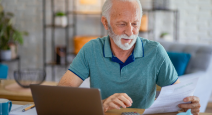 Old man looking into his finances in front of his laptop