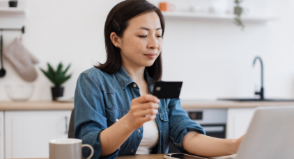 Woman holding her credit card in front of her laptop