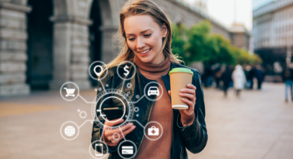 woman looking at her phone holding a cup of coffee in her other hand
